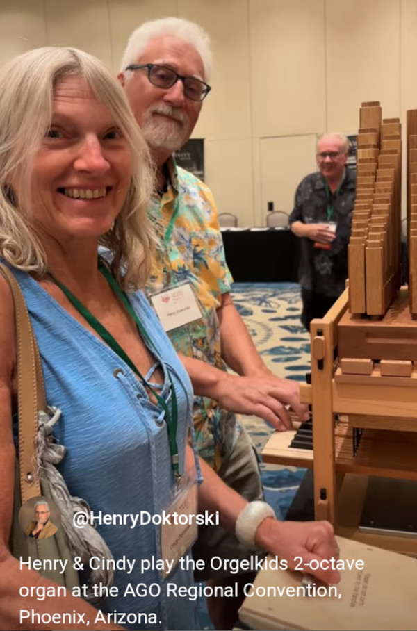 Cindy pumps the bellows and Henry plays a tune on the two-octave Orgelkids organ at the Vendor's Display Area.